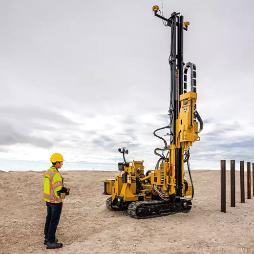 Operador utilizando el sistema de control y guiado 3D Trimble Groundworks en un sitio de construcción con una pilotadora amarilla en funcionamiento, demostrando precisión y eficiencia en la obra