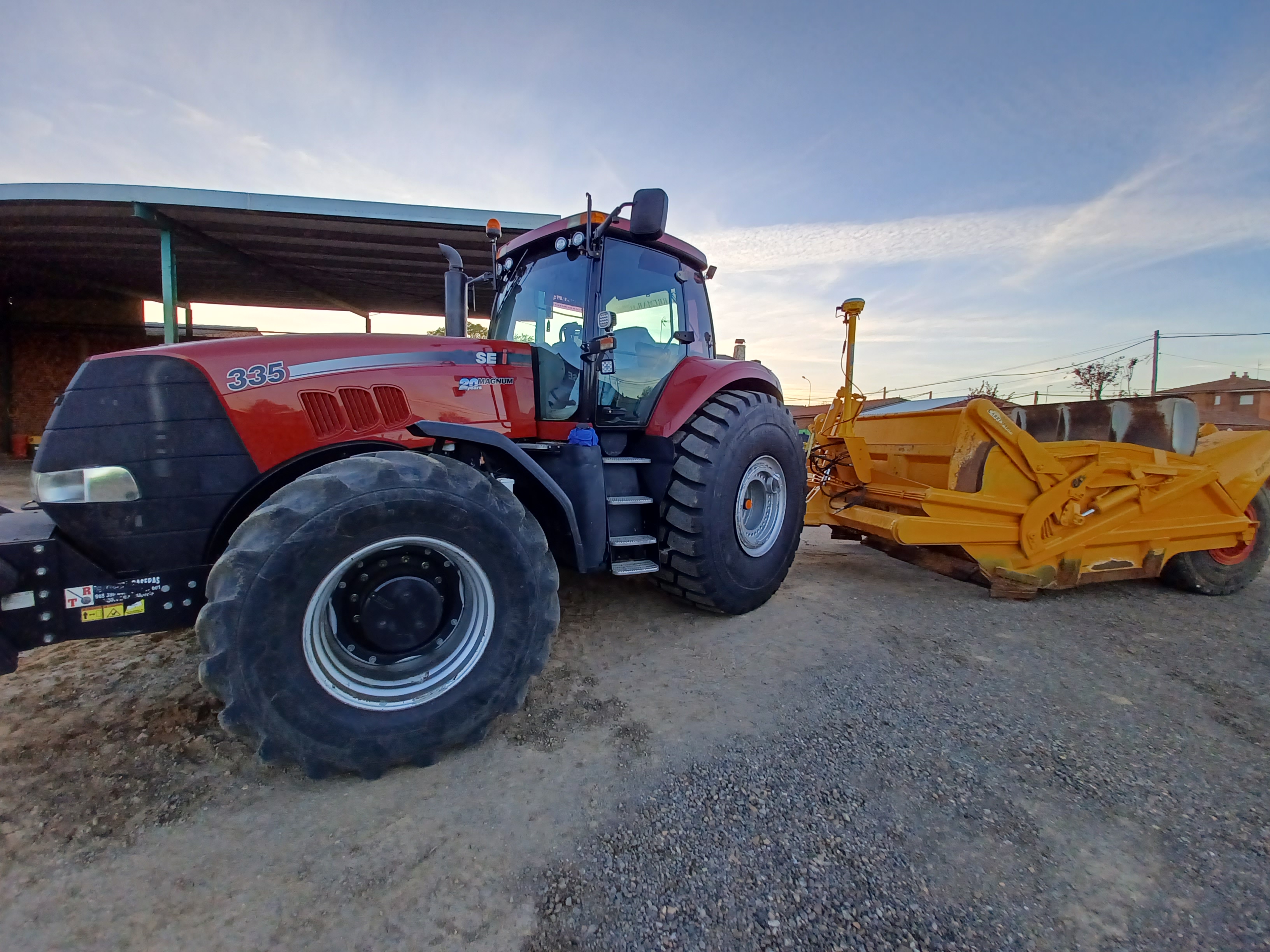 Tractor agrícola rojo equipado con el sistema 3D Trimble Earthworks, demostrando tecnología avanzada para la construcción de precisión