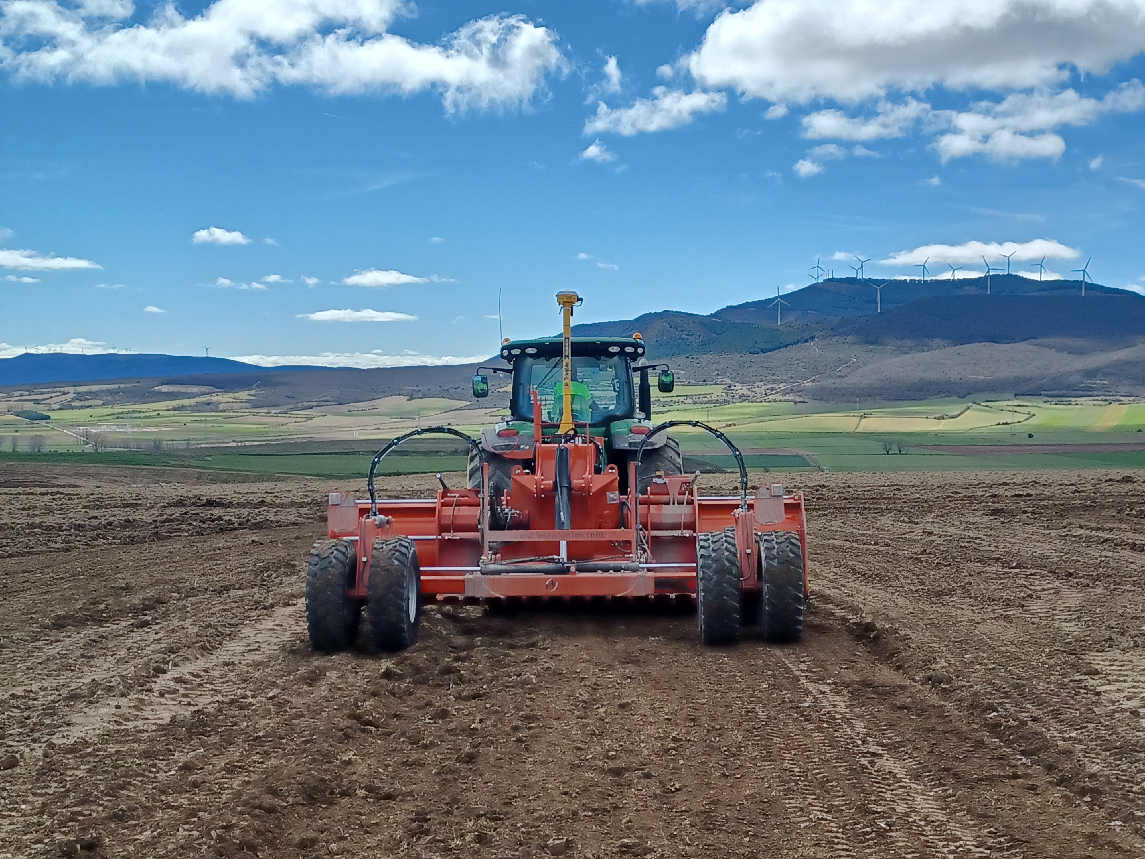 Vista trasera de un tractor agrícola moderno equipado con el sistema 3D Trimble Earthworks, trabajando para realizar labores de construcción y nivelación en terrenos