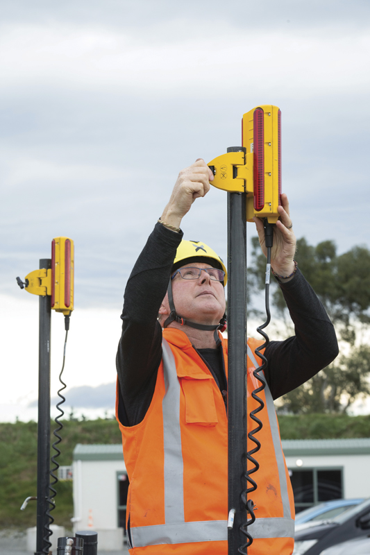 Operador profesional en chaleco de alta visibilidad montando fácilmente el sistema Trimble Earthworks GO! para un nivelado preciso en un sitio de construcción, demostrando la facilidad de instalación y desinstalación del equipo